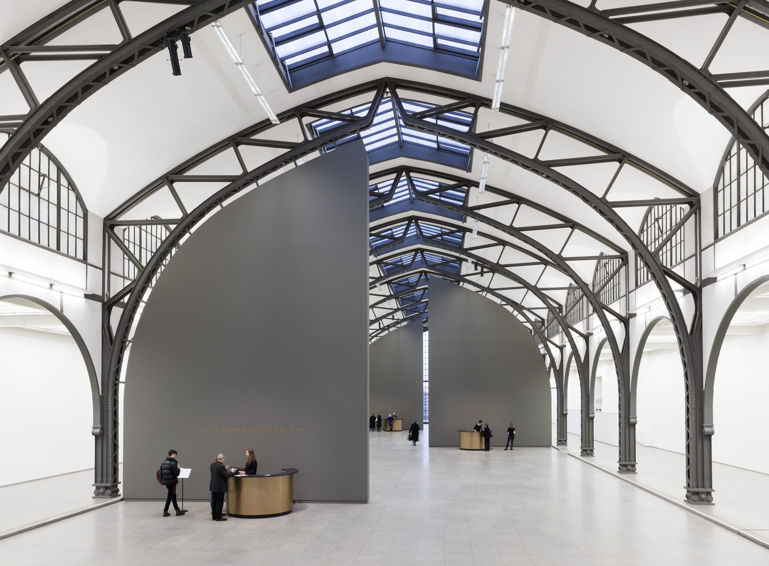 Adrian Piper, The Probable Trust Registry: The Rules of the Game #1-3, 2013-2017, Installation + Group Performance: 3 grey walls reaching from floor to the ceiling, 3 golden circular desks, golden embossed letters, 3 standing desks, 3 lean stools, computer system, 3 receptionists (one behind each desk). Adaptable Dimensions. Detail: The Rules of the Game #1. Staatliche Museen zu Berlin, Nationalgalerie / Thomas Bruns. Sammlung Staatliche Museen zu Berlin, Nationalgalerie. 2016 Schenkung der Freunde der Nationalgalerie. © Adrian Piper Research Archive Foundation Berlin. © APRA Foundation Berlin